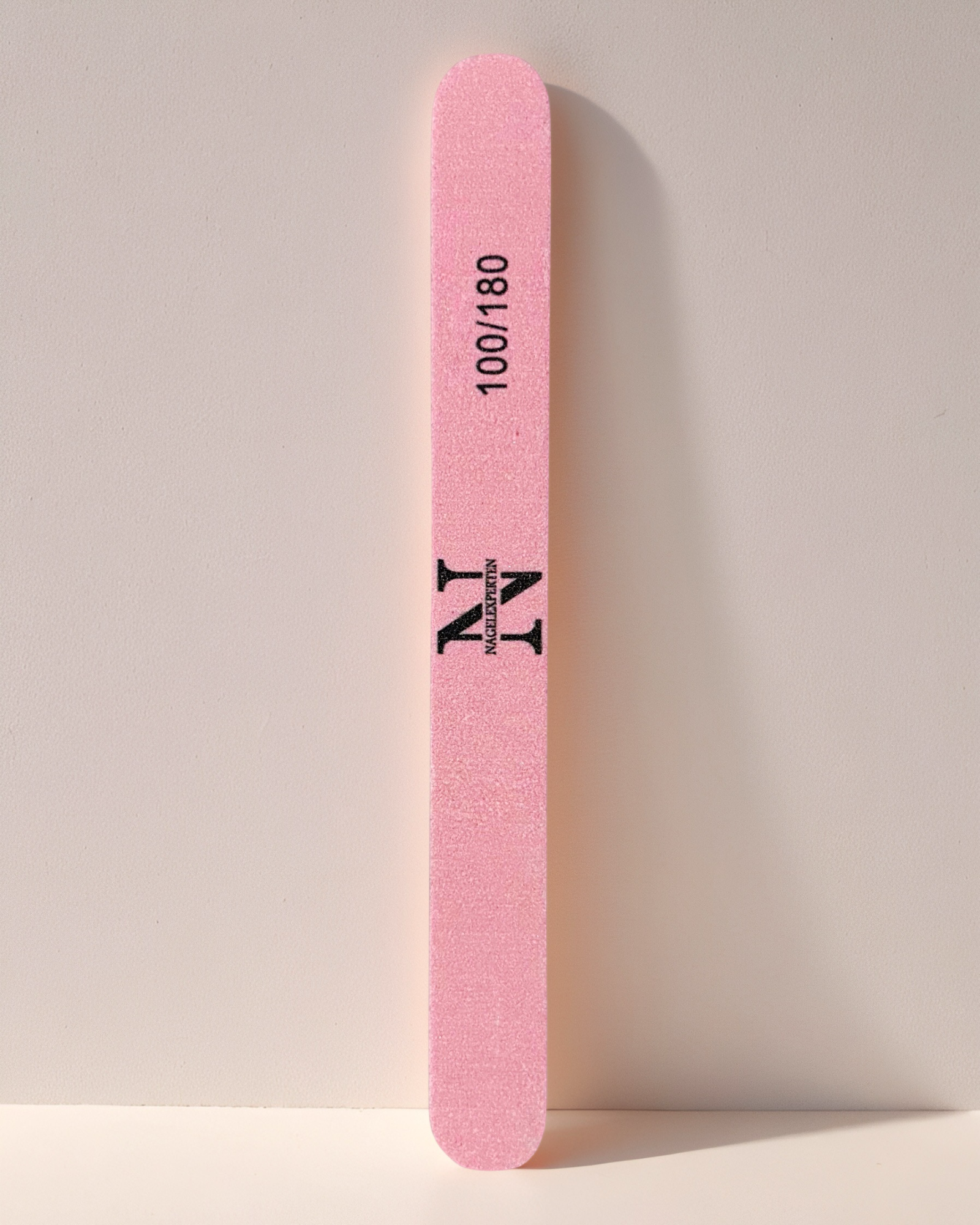 Rosa nagelfil med 100/180 grit som lutar mot en vägg.