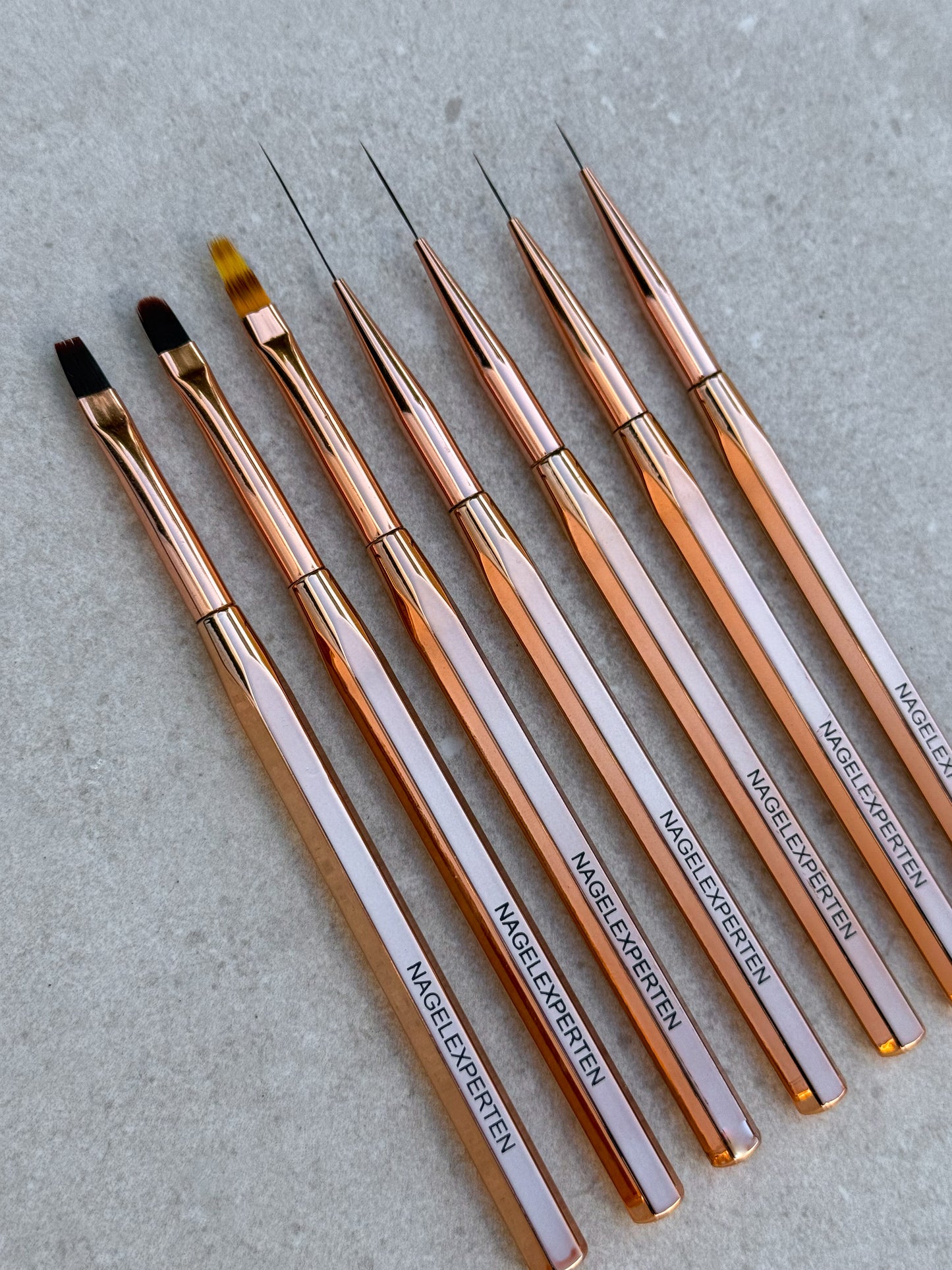 Kit med fyra stycken liner penslar, två gelpenslar och en ombrepensel för naglar i roséguldig färg.