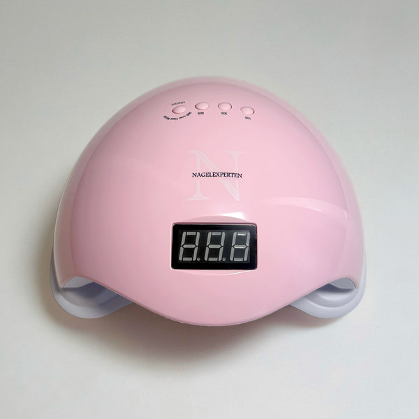 En rosa uv gel nagellampa med vit bakgrund för härdning av gellack och builder gel.